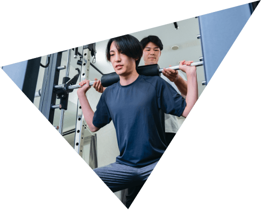 トレーナーのサポートでバーベルトレーニングをする様子